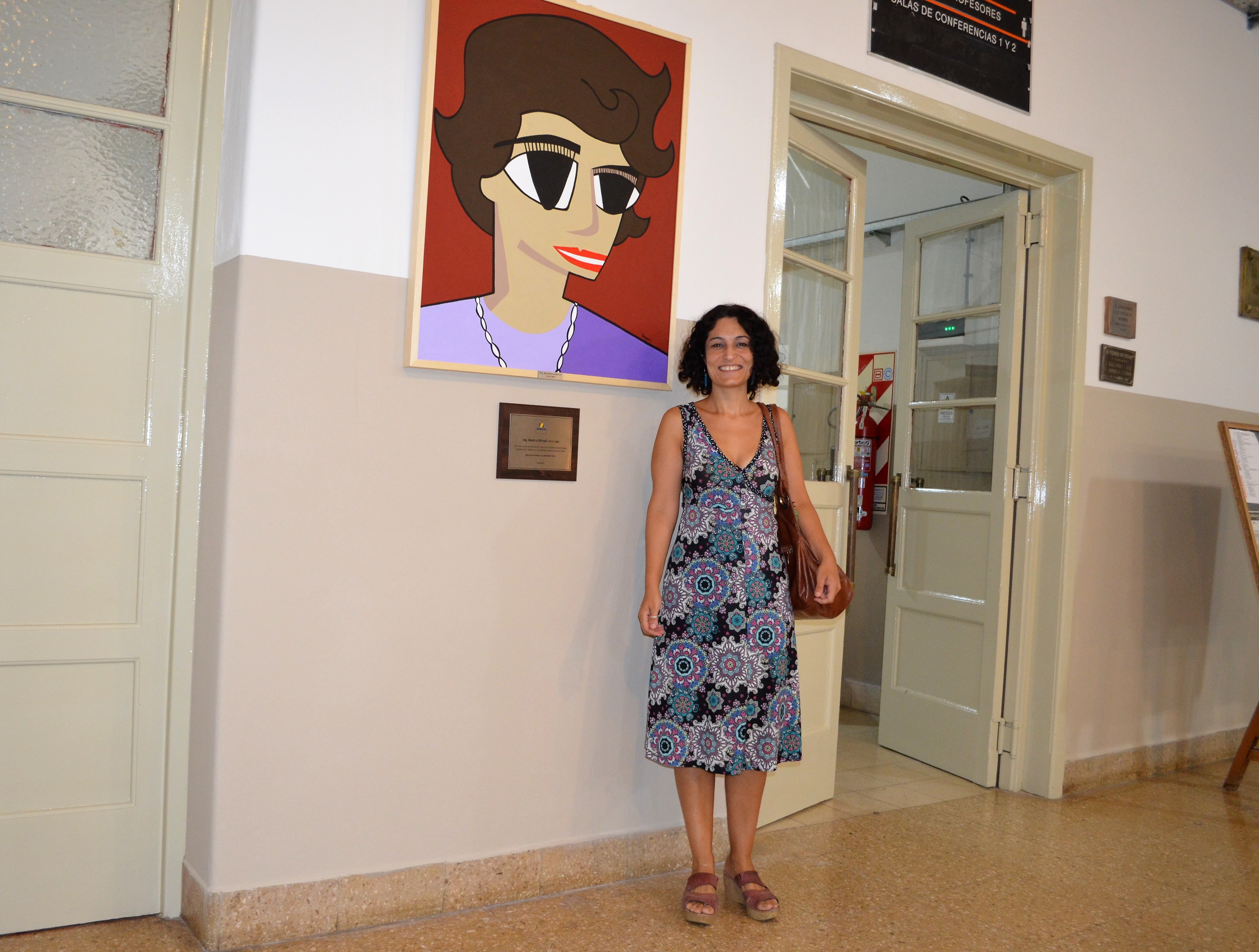 La investigadora Paula Bergero junto al cuadro de Beatriz Ghirelli, inaugurado el 12 de marzo último en el Departamento de Electrotecnia.